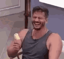 a man with a beard is sitting in a chair holding a banana and smiling .