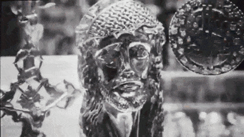 a black and white photo of a statue of jesus with a cross in the background