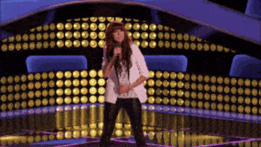 a woman is singing into a microphone on stage