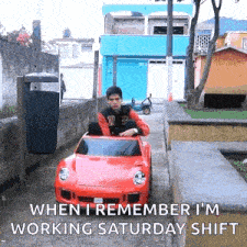 a man is sitting in a small red toy car .