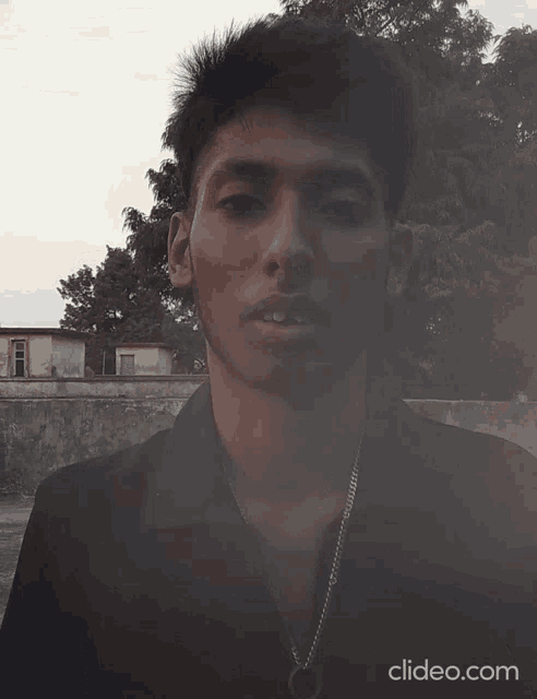 a young man wearing sunglasses and a black shirt looks at the camera with clideo.com at the bottom of the screen