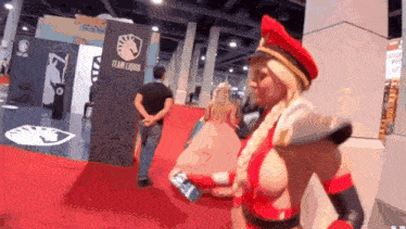 a woman in a costume is standing on a red carpet in front of a team liquid sign