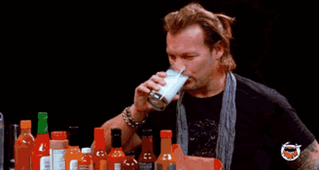 a man with a ponytail is drinking from a glass