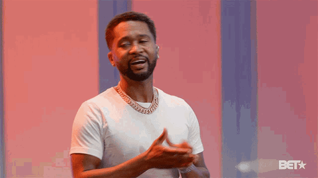 a man wearing a white shirt and a gold chain is clapping