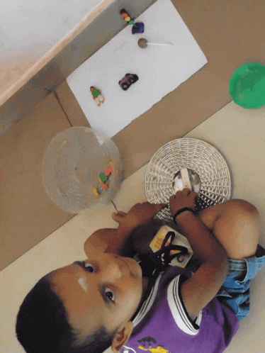 a young boy in a purple shirt is playing with a basket