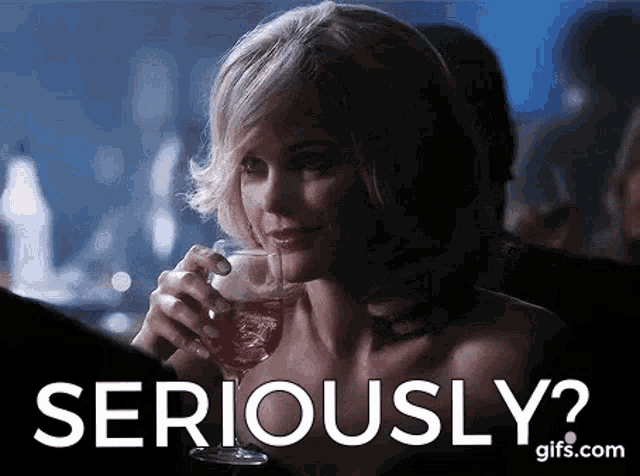 a woman is holding a glass of wine and asking if she is seriously ?