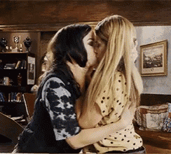 two women are kissing in a living room while hugging each other