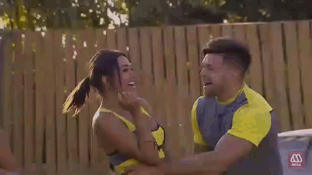 a man and a woman are hugging each other in front of a yellow building with a m on it ..