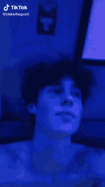 a man 's face is lit up with a blue light and the words tiktok are on the bottom