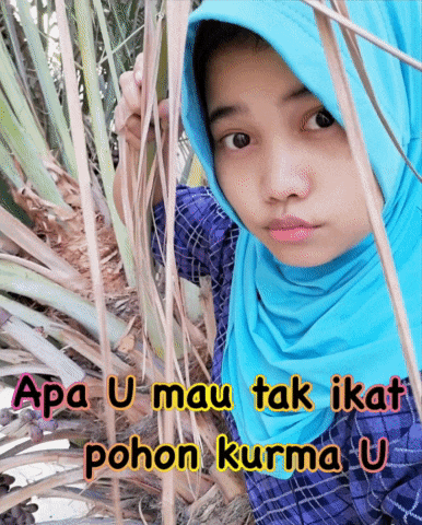 a girl wearing a blue hijab stands in front of a tree