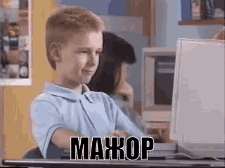 a young boy is sitting at a desk in front of a computer with the word makor written on it .
