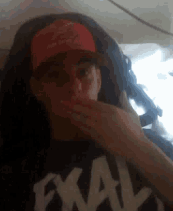 a man wearing a red hat covering his mouth with his hand