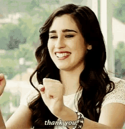 a woman is smiling and holding her fist in the air and saying thank you .