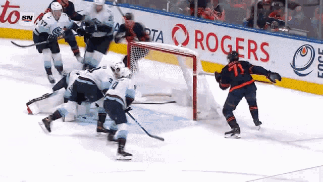a hockey game is being played in front of a rogers banner