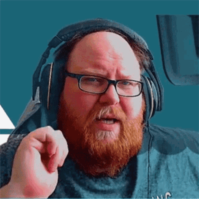 a bearded man wearing glasses and headphones is making a funny face .