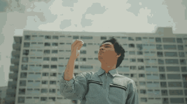 a man in a striped shirt is looking up at the sky