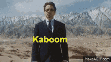 a man in a suit and tie stands in front of mountains with the word kaboom written on the screen