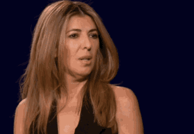 a woman in a black top is looking at the camera with a surprised look on her face