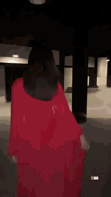 a woman in a red dress is dancing in a dark room