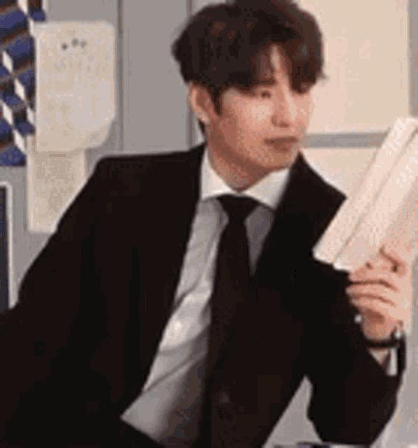 a man in a suit and tie is reading a book .
