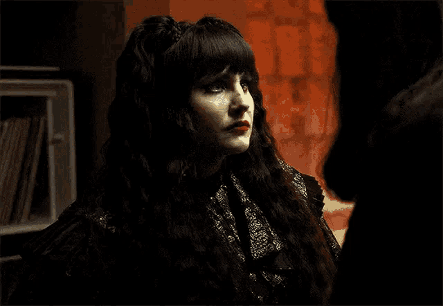 a woman with long black hair and red lips is standing next to another woman .