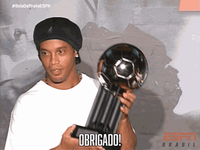 a man holding a trophy with the word obrigado on it