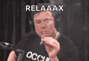 elon musk is smoking a cigarette in front of a microphone .