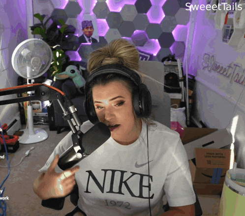 a woman wearing headphones and a white nike 1972 shirt
