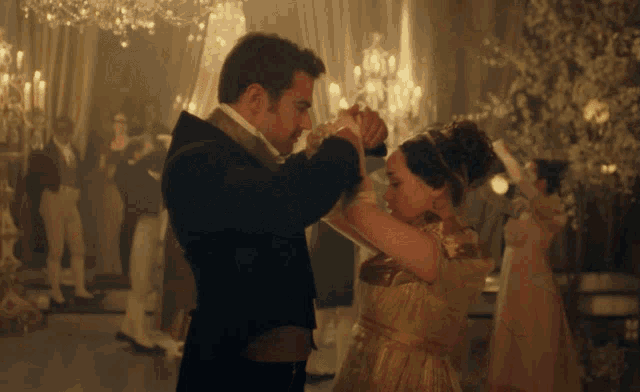 a man and a woman are dancing in a ballroom with other people