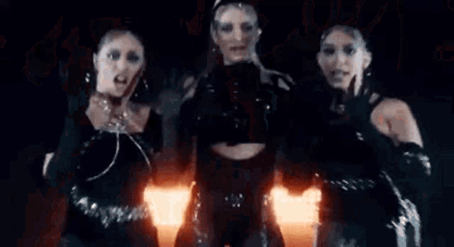 a group of women are standing next to each other in front of a fire and smoke .