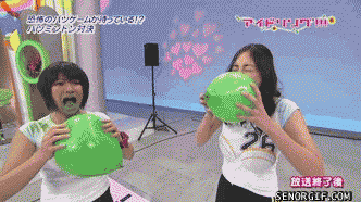two women are blowing up green balloons in front of a sign that says senorfgif.com