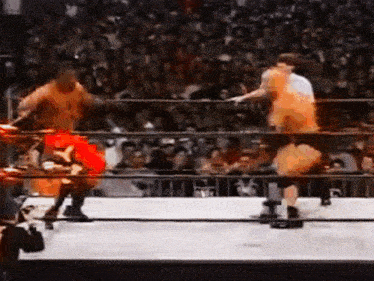 two wrestlers are fighting in a ring with a crowd watching