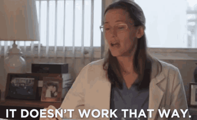 a woman in a lab coat is sitting at a desk and says it does n't work that way