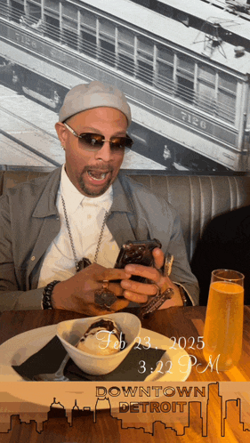 a man sits at a table with a bowl of food and a sign that says downtown detroit