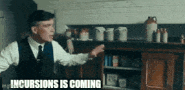 a man in a suit and tie is standing in a kitchen and pointing at something .