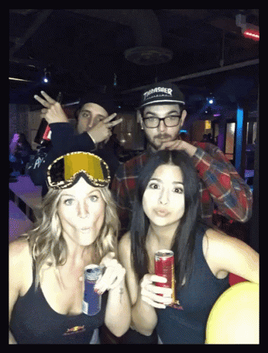 a man wearing a thrasher hat is standing next to two women