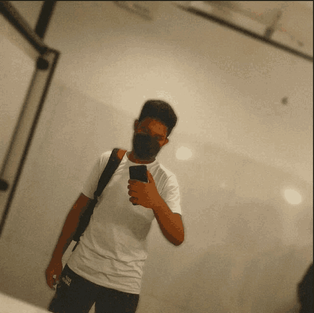 a man wearing a mask takes a picture of himself in a bathroom mirror