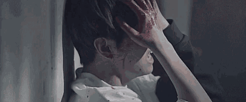 a man with blood on his face is holding his head while a woman holds his neck .