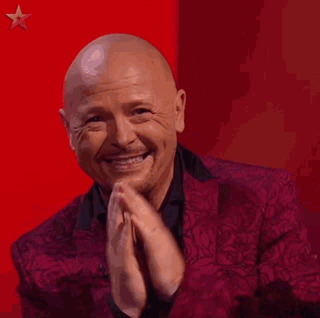 a man in a purple suit is covering his face with his hands .