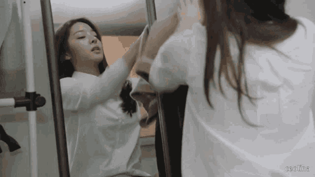 a woman is looking at herself in a mirror with the words ceolina written below her