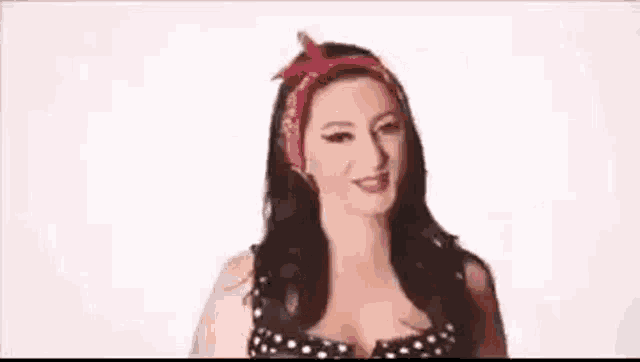 a woman in a polka dot dress and a red bandana is smiling .