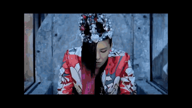 a man with a crown on his head is wearing a colorful jacket