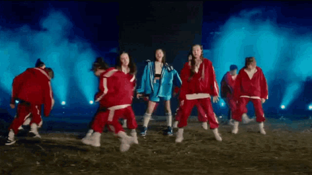 a group of people are dancing on a stage in front of a blue light