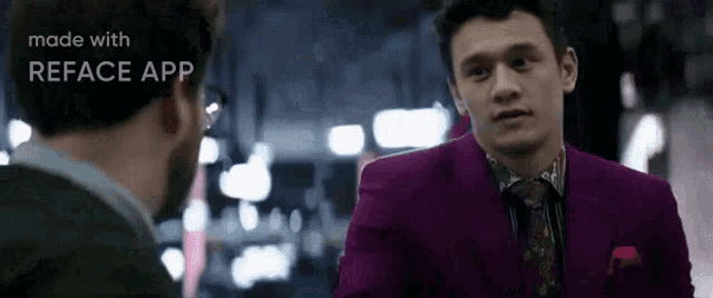 a man in a purple suit is talking to another man