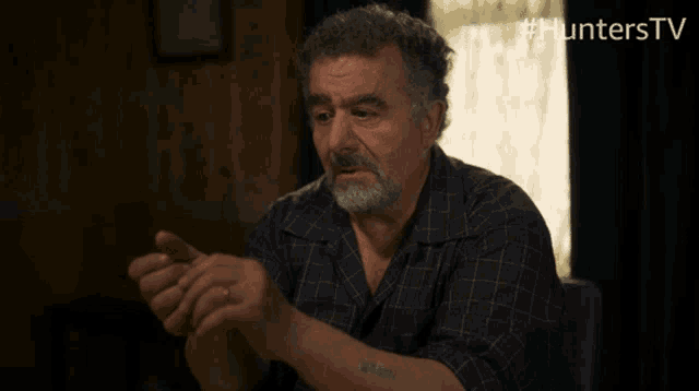 a man with a tattoo on his arm is sitting in front of a sign that says hunters tv