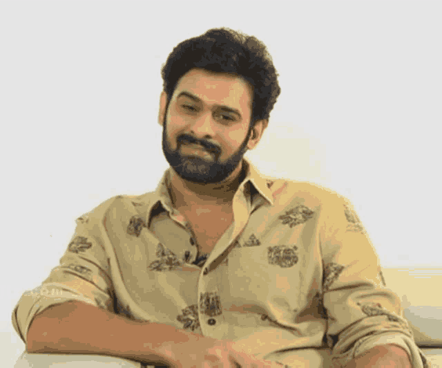 a man with a beard is wearing a tan shirt with a floral print