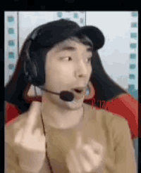 a man wearing headphones and a hat is giving the middle finger while making a funny face .