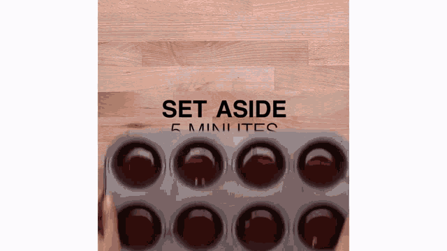a person is holding a muffin pan with the words set aside 5 minutes written on it .