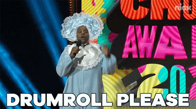 a man in a baby costume holds a microphone in front of a sign that says drumroll please