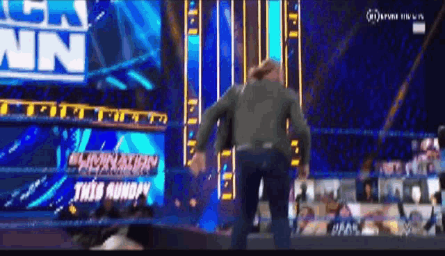 a man is walking out of a wrestling ring during a wrestling match .